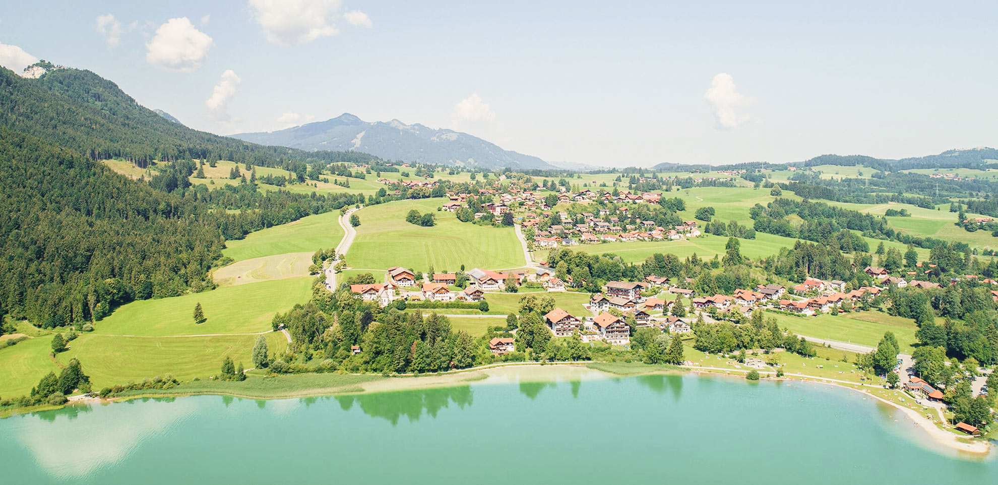 Luftbild mit Blick ans Ufer des Weissensee im Allgäu und dem Ort Oberkirch mit Hotel Steigmühle